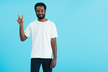Fototapeta premium smiling african american man showing peace symbol isolated on blue