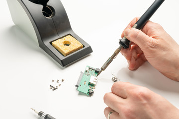 Technician soldering an electronic component with a soldering iron