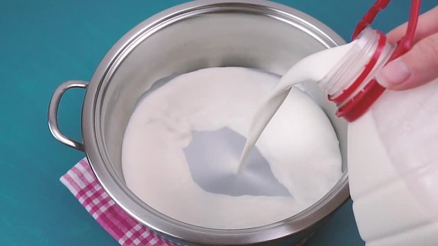 Pouring milk in a pot. Blue background