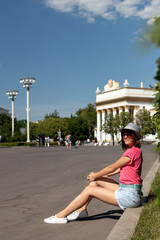 Woman in hat sitting on the border in the park, Moscow.