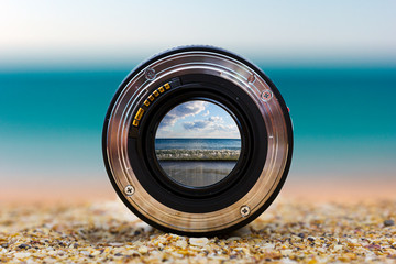 View of the sea surf through a photographic lens lying on a sandy beach on a sunny day. - obrazy, fototapety, plakaty