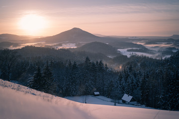 Sonnenuntergang in Winterlandschaft mit Hütte und Nebel