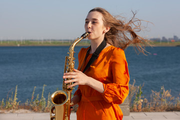 Young woman with saxophone with nature background