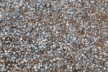 Gravel on ground. White, black and grey stones on earth. Abstract background.
