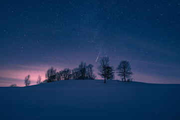 Hügel mit Sternenhimmel im Winter bei Schnee