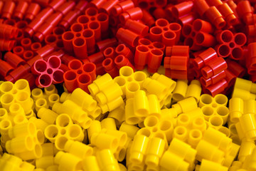 Obraz premium Plastic bricks of yellow and red on a background. Details of toys. Close up.