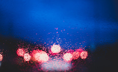 Blurred cars lights from inside a car with drops on the window