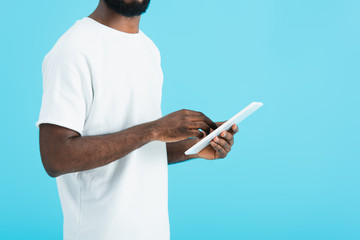 cropped view of african american man in white t-shirt using digital tablet isolated on blue