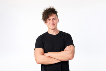Fototapeta premium Portrait of attractive young stylish cheerful man wearing a black cotton T-shirt posing in studio. Studio shot on a white background.