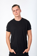 Fototapeta premium Attractive stylish smiling young man wearing a black cotton shirt posing in studio on white background. Studio portrait.