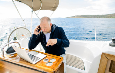 Digitaler Nomade mit Laptop telefoniert energisch auf einem Segelboot