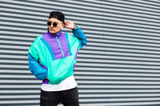 Back in time 90s 80s. Stylish young man in a retro jacket and with a vintage cassette player, on the background of a steel wall, fashion trends, street image