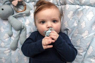 Beautiful baby in the crib with a pacifier before a sleeping. View from above.