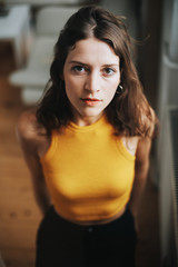 high-angle image of brunette woman wearing a yellow top looking up into the camera