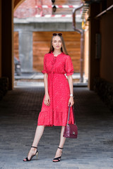 Obraz premium Pretty girl in red dress walking on the street in old town