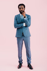 thoughtful african american businessman in suit, isolated on pink