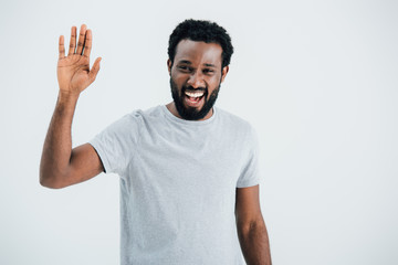 cheerful african american man in grey t-shirt waving isolated on grey