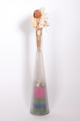 Interior vase with colorful decorative stones and dried flowers isolated