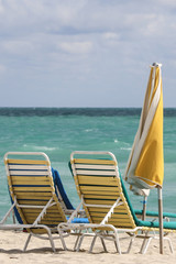 A couple of beach chairs and yellow umbrela in Miami beach
