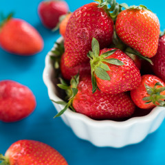 fresh bright strawberries in a bowl top view on a blue background
