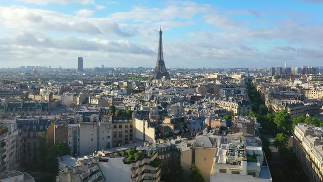 Aerial, reverse, drone shot, tilting up and revealing french buildings, architecture and the Eiffel tower, in the city of Paris, on a sunny, summer day, in France