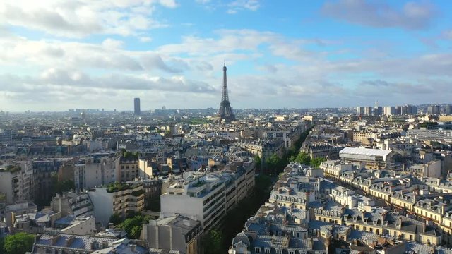 Aerial, tracking, drone shot, of the Eiffel tower, overlooking traffic on french streets, buildings and architecture, in the city of Paris, on a sunny, summer day, in France