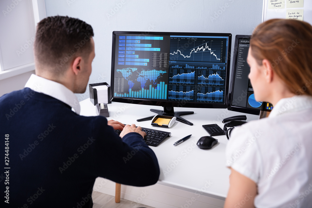 Poster two businesspeople examining graph on computer