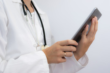 Young woman doctor holding tablet computer in her hands on white background. Health care concept.