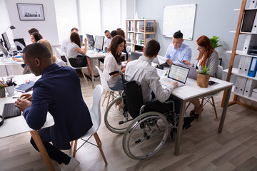 Disabled Businessman Sitting On Wheelchair Using Laptop - obrazy, fototapety, plakaty