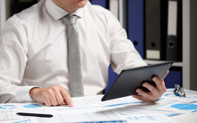 Businessman working with tablet pc, calculating, reading and writing reports. Office employee, table closeup. Business financial accounting concept.