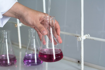 The laboratory technician collects the reagent in his hands with a pipette, substances of blue and...