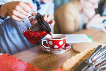 berry tea is poured into a red mug. red tea with berries is poured into a glass with white peas. Russian old-fashioned dishes in the restaurant. red and white polka dot dishes and a kettle