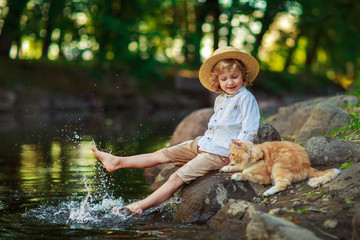 Little curly boy with a redhead cat, outdoor summer day