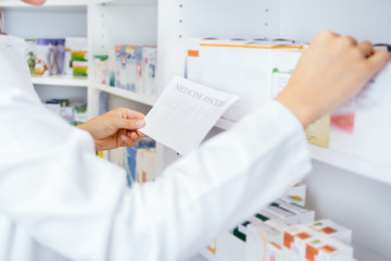 Medical pharmacists searching for medication by prescription in drugstore