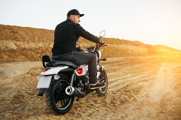 Obraz na płótnie Canvas Smiling happy biker in sitting on motorcycle on road