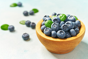 Fresh blueberries in a wooden bowl on a light background, with copy space. Concept for healthy eating and nutrition.