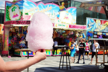amusement park eating white cotton candy. enjoying a day at amusement park with fresh cotton candy...