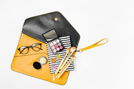 Flat lay of female fashion accessories,  makeup products and handbag on orange colors. Beauty and fashion concept