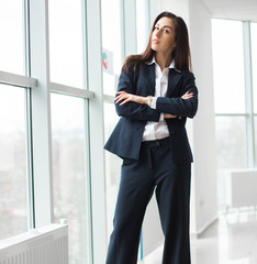 Young businesswoman sitting at workplace and reading paper in office