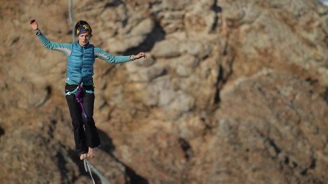 A young woman is on the slackline at high altitude.