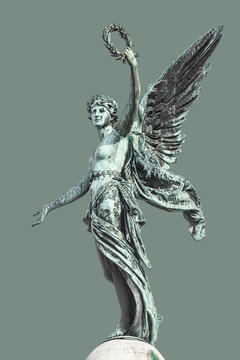 Top column statue of sensual renaissance era angel with wings and flowers wreath in Vienna, isolated at green background, Austria