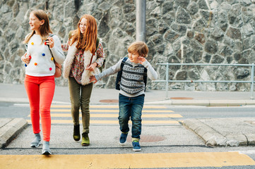 Group of 3 kids crossing the road, walking back to school, wearing backpacks