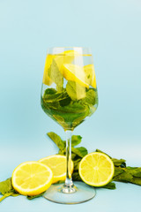 Glass of homemade lemonade. Refreshing summer drink on blue background. Ingredients: soda, lime, lemon, mint.