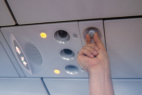 Hand man up to adjust console panel. The air condition, light, low cost airline seat. While on board of an aircraft, selective focus. Blur background color vintage style.