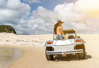 Beautiful happy young woman with buggy ride through the dunes of the coast of Brazil.