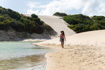 Beautiful happy young woman strolling along the dunes of the coast of Brazil. Young woman walking on the sand of the dunes.