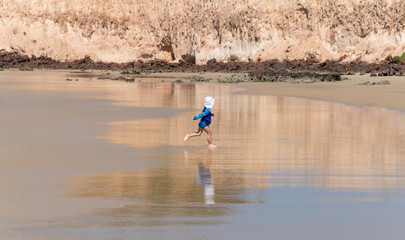 Child playing on the beach. Small child having fun on the sands and beach water.