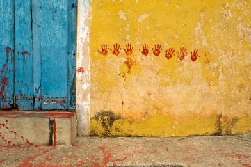 Red hands printed on yellow wall, Mexico