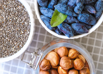 granola, nuts and fresh berries in a bowls white on a wooden background. top view. The concept of...