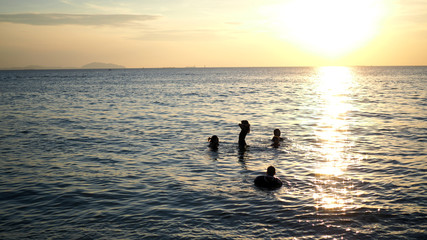 Children playing at the sea during sunset.